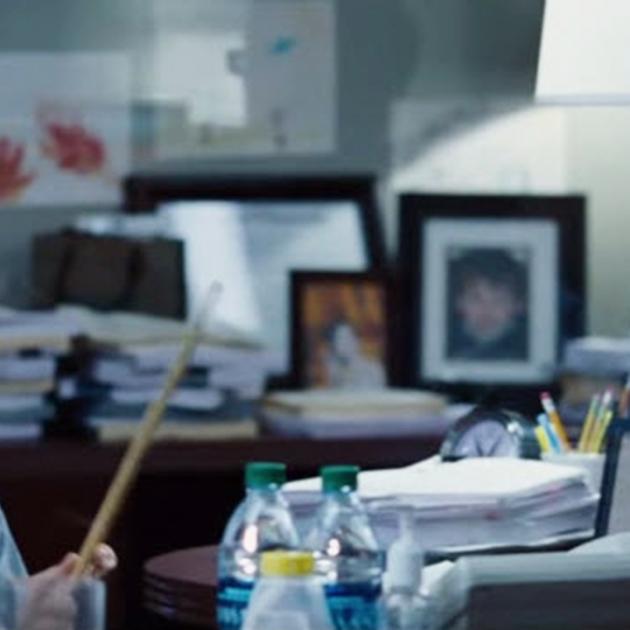 Picture of a guy in an office playing with drumsticks