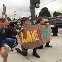 Protesters with signs down on one knee