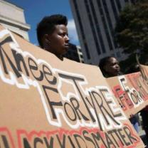 Black people holding a banner that says "Knee for Tyye, Black Kids Matter"