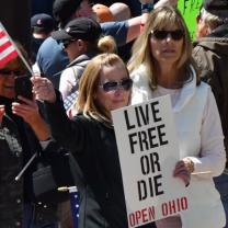 Woman holding sign saying Live Free or Die