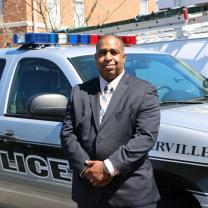 Black man standing next to police car