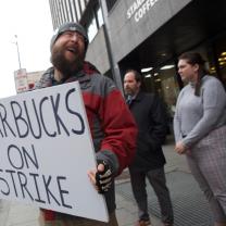 Guy outside Starbucks holding a sign saying Starbucks on strike